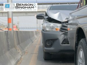 Car with a crumpled hood after a rear-end accident on a city road, beside a concrete barrier