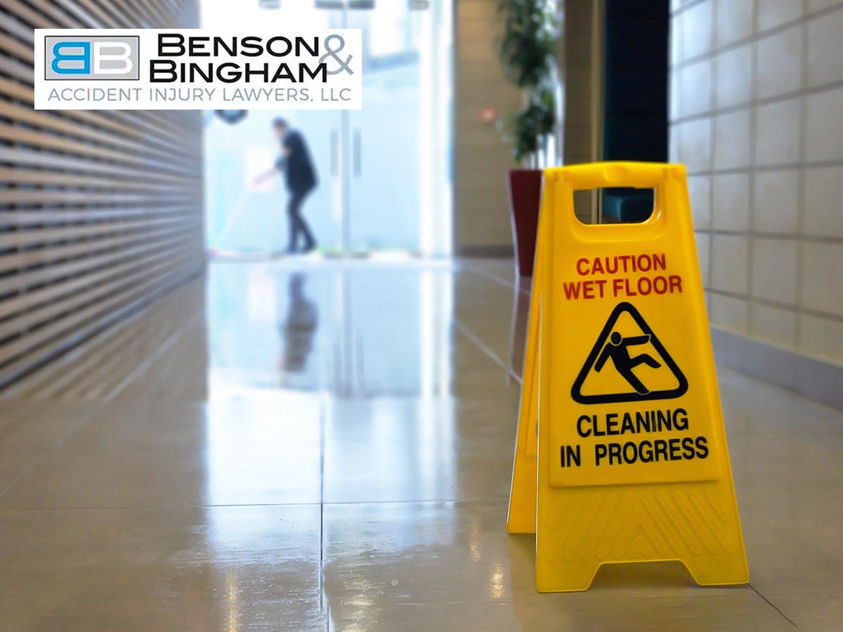 Accident prevention sign indicating a wet floor with Benson & Bingham branding in the background