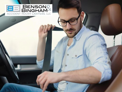 Man fastening seatbelt to reduce risk of whiplash injury, Benson & Bingham Accident Injury Lawyers logo visible