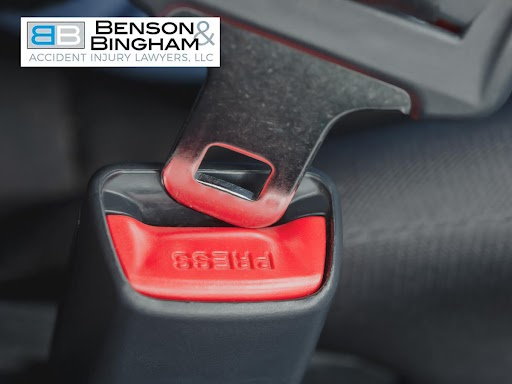 Close-up of seatbelt buckle to emphasize safety and prevention of whiplash injury, Benson & Bingham Accident Injury Lawyers logo visible.