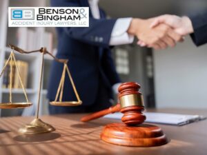 Lawyer and client shaking hands after reaching a Settlement, with a gavel and scales of justice on the desk