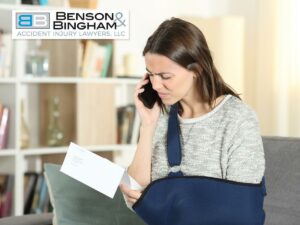 "Woman with an arm injury reviewing a letter and discussing her worker's compensation claim on the phone